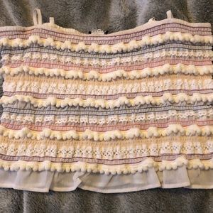 multi colored top with embroidery and pom poms